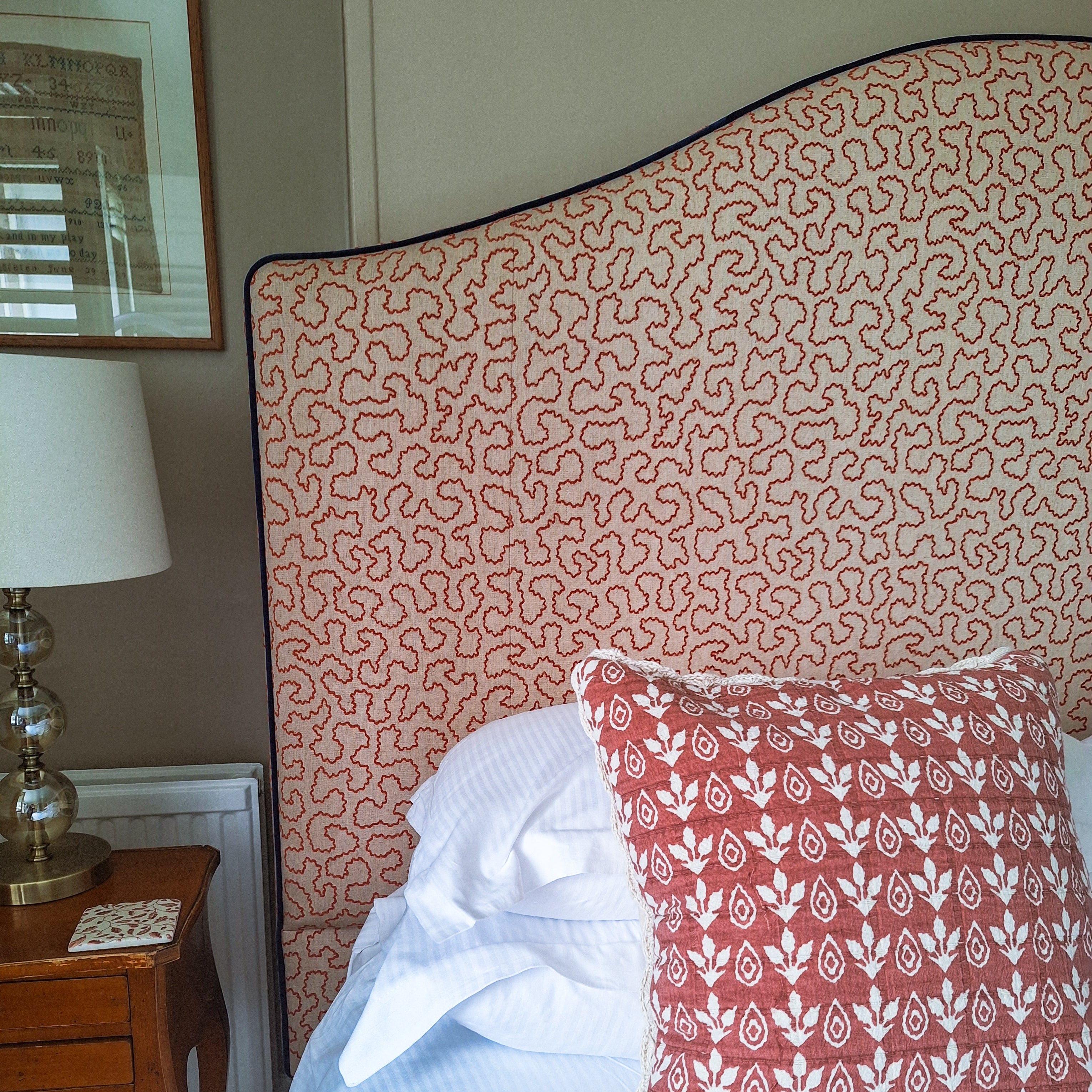 Bed with patterned headboard and pillow in a bedroom setting