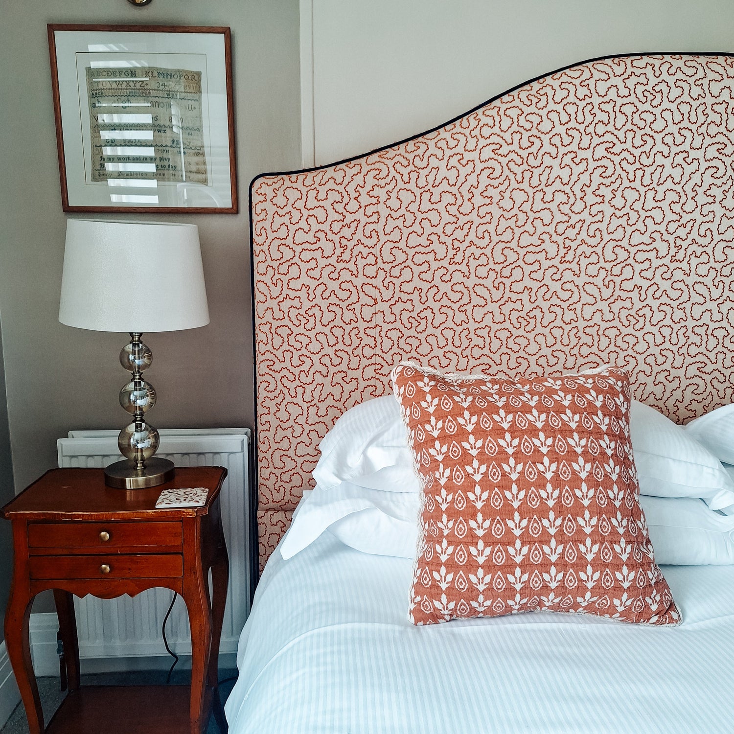 Upholstered headboard with piped edge in patterned fabric by North End Interiors